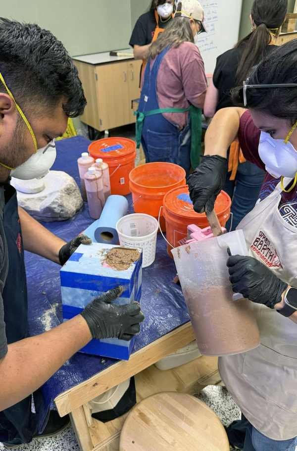 Participants at a community bone casting workshop mixing concrete and preparing molds
